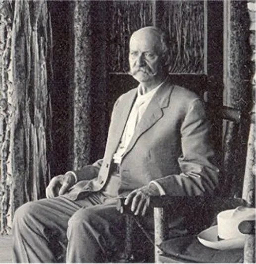 A black and white medium shot of A.V. Hunter sitting in a wooden chair.